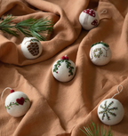 Kerstballen in vilt van Gry & Sif met geborduurde motieven op een okerkleurige doek