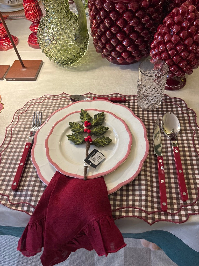 Kersttafel met geschulpte borden, geruite placemat en bordeaux servet